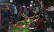 Consumers and sellers are seen at a temporary street-side evening vegetable market in Kolk...