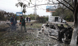Men see branches broken by Russian shelling on the grounds of the Salvation Church in Vysh...