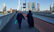Two women walk along the pedestrian path of the Erasmus Bridge in Rotterdam, Netherlands,...