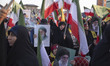 Veiled Iranian women hold portraits of Iran's Supreme Leader, Ayatollah Ali Khamenei, and...