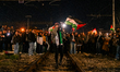 A female protester on the railway tracks leads chants with a megaphone while others wave P...