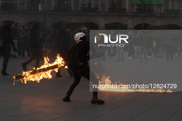 An anarchist holds a burning wooden beam during a protest commemorating the 57th anniversary of the 1968 Student Massacre at the Plaza de la... by Eyepix/NurPhoto