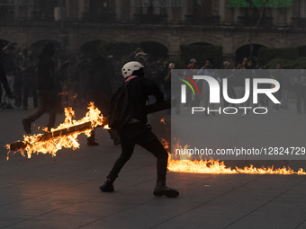 An anarchist holds a burning wooden beam during a protest commemorating the 57th anniversary of the 1968 Student Massacre at the Plaza de la... by Eyepix/NurPhoto