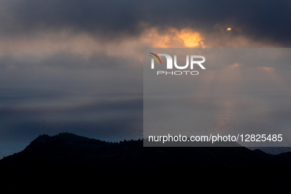 The sun is partially covered by clouds over the Ionian Sea at dusk near Myrtos Beach on September 5, 2025 in Kefalonia, Greece. 