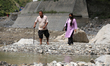 Travelers cross over a section of BP Highway, which now turns into a flowing river followi...