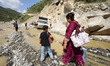 Nepali travelers wade through a flooded section of the BP Highway in Kavrepalanchowk Distr...