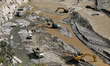 Heavy load construction vehicles make a diversion in the Roshi River along the BP Highway...