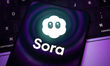 The Sora app logo appears on the screen of a smartphone placed on a computer keyboard, whi...