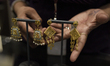 A showroom staff showcases a gold jewelry earring to a customer at Kalyan Jewellers showro...