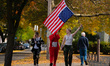 A person waves an upside-down American flag while walking with other participants dressed...
