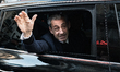 France's former president Nicolas Sarkozy waves to his supporters as he leaves his residen...