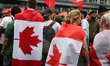 Demonstrators drape themselves in Canadian flags during the 'Canada First' anti-immigratio...
