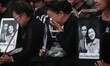 A woman cries and holds photographs of Thailand's Queen Mother Sirikit as people react fol...