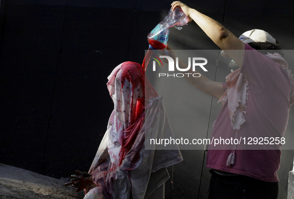 A pro-Palestinian activist pours red paint, simulating blood, onto a dummy during a protest outside the Indie Rocks Forum in Mexico City, Me... by Gerardo Vieyra/NurPhoto