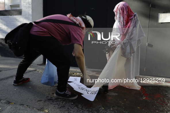 A pro-Palestinian activist pours red paint, simulating blood, onto a dummy during a protest outside the Indie Rocks Forum in Mexico City, Me... by Gerardo Vieyra/NurPhoto