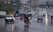 People cross the road in Kathmandu, Nepal, on October 30, 2025, wearing umbrellas as rain...