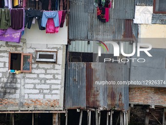 Laundry hangs above fragile, uneven homes built from patched materials along the Duri River at Tanjung Selor Street in Central Jakarta, Indo... by Donal Husni/NurPhoto