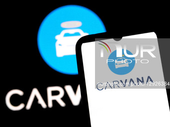 The Carvana logo appears on a smartphone screen and as the background on a laptop computer screen in this photo illustration in Athens, Gree... by Nikolas Kokovlis/NurPhoto