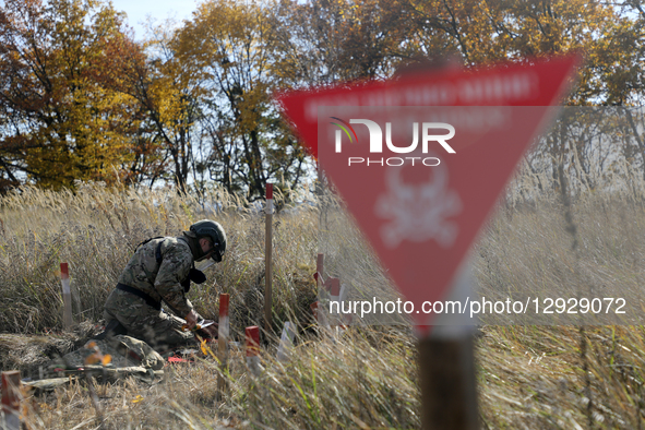 A participant works near a ''Danger, Mines'' sign during humanitarian demining training for war veterans in Kyiv, Ukraine, on October 30, 20... by Yuliia Ovsiannikova/Ukrinform/NurPhoto
