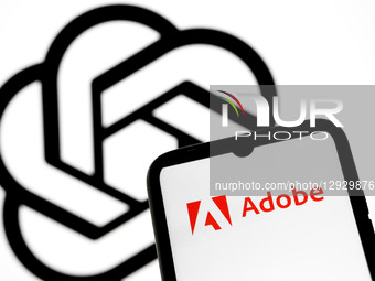 The Adobe logo appears on a smartphone screen, and the OpenAI logo displays as the background on a laptop screen in this photo illustration... by Nikolas Kokovlis/NurPhoto