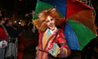 A reveler dressed as a cat holding an umbrella marches during the 52nd annual Village Hall...