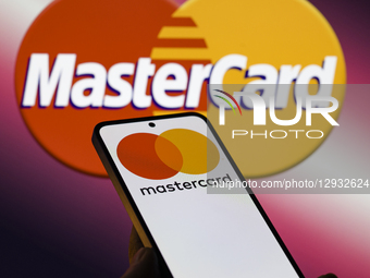 The Mastercard logo is displayed on a mobile phone with the company's branding seen in the background in this photo illustration in Brussels... by Jonathan Raa/NurPhoto