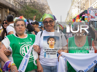 Three retired women, one of them wearing a Maradona T-shirt, walk down one of the avenues during the Pride march in 2025  by Guillermo Castro/NurPhoto