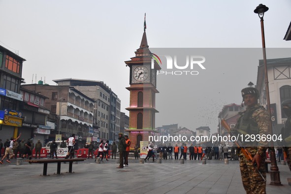 An Indian paramilitary soldier stands guard as participants run near the Clock Tower (Ghanta Ghar) during the Kashmir Marathon in Srinagar,...