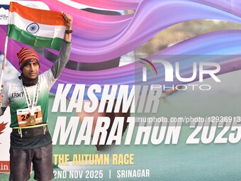 A participant carries India's national flag as he takes a picture near the billboard of the Kashmir Marathon 2025 in Srinagar, Jammu and Kas... by Firdous Nazir/NurPhoto