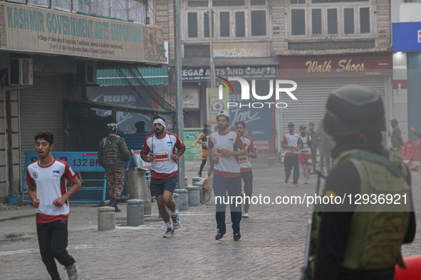 An Indian paramilitary soldier stands guard as participants run during the Kashmir Marathon in Srinagar, Jammu and Kashmir, on November 2, 2... by Firdous Nazir/NurPhoto