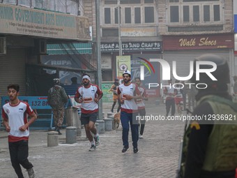 An Indian paramilitary soldier stands guard as participants run during the Kashmir Marathon in Srinagar, Jammu and Kashmir, on November 2, 2... by Firdous Nazir/NurPhoto