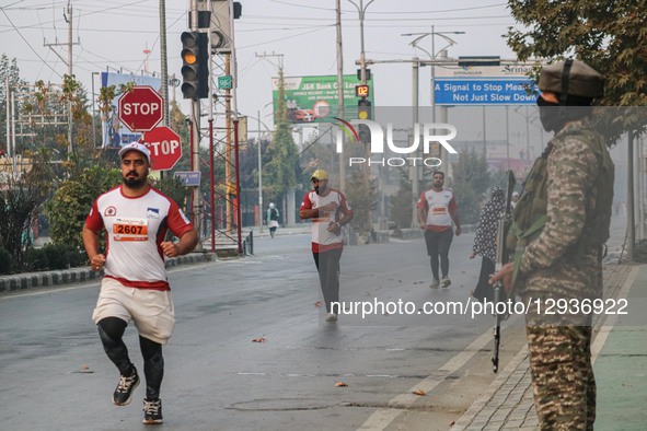 An Indian paramilitary soldier stands guard as participants run during the Kashmir Marathon in Srinagar, Jammu and Kashmir, on November 2, 2... by Firdous Nazir/NurPhoto