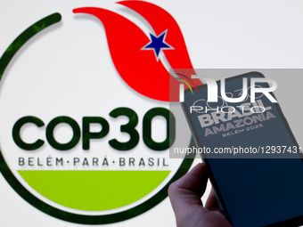 The COP30 Brazil Amazonia logo is displayed on a mobile phone with the COP30 seen in the background in this photo illustration in Brussels,... by Jonathan Raa/NurPhoto