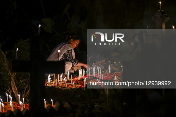 A Christian woman lights candles by the grave of a relative during All-Soul's Day at a graveyard in Dhaka, Bangladesh, on November 2, 2025.  by Zabed Hasnain Chowdhury/NurPhoto