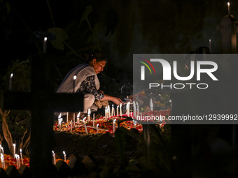 A Christian woman lights candles by the grave of a relative during All-Soul's Day at a graveyard in Dhaka, Bangladesh, on November 2, 2025.  by Zabed Hasnain Chowdhury/NurPhoto