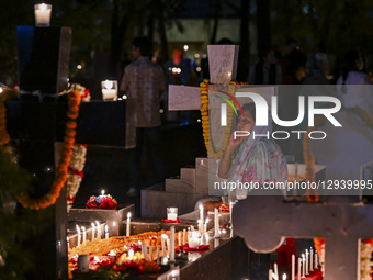 A Christian woman lights candles by the grave of a relative during All-Soul's Day at a graveyard in Dhaka, Bangladesh, on November 2, 2025.  by Zabed Hasnain Chowdhury/NurPhoto