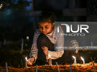 A Christian girl lights candles by the grave of a relative during All-Soul's Day at a graveyard in Dhaka, Bangladesh, on November 2, 2025.  by Zabed Hasnain Chowdhury/NurPhoto