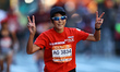 Runner Toshiko Go of Japan flashes peace signs as she heads up First Avenue during the 202...