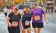 Three women all smile as they reach the 17th mile point of the 2025 New York City Marathon...