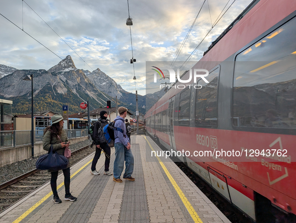 A red DB Regio train arrives at the Ehrwald Zugspitzbahn station platform, where travelers wait in Ehrwald, Tyrol, Austria, on November 1, 2... by Michael Nguyen/NurPhoto