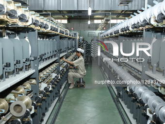 A worker works on intelligent textile equipment in Suqian City, Jiangsu Province, China, on November 3, 2025.  by Costfoto/NurPhoto