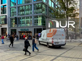 A white Trans-o-flex delivery van with orange graphics drives in a busy pedestrian zone near a Douglas store and other retail outlets in Mun... by Michael Nguyen/NurPhoto