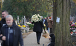 A man with a large bouquet of roses and a panhandler are seen at the Brodno Cemetery in Wa...