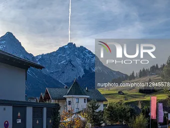 A vertical contrail from an aircraft streaks directly upward from a snow-dusted Alpine peak, towering over village houses in Lermoos, Tyrol,... by Michael Nguyen/NurPhoto