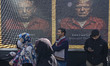 Iranian protesters stand under a display featuring the portraits of the U.S. President, Do...
