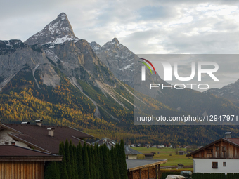 Traditional Tyrolean village houses with yellow facades and red roofs are visible beneath the dramatic, snow-dusted peaks of the Zugspitz ma... by Michael Nguyen/NurPhoto