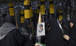 Veiled Iranian women stand together in front of a portrait of Iran's Supreme Leader, Ayato...