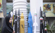 Veiled Iranian women sit together under scale models of Iran-made ballistic missiles and t...