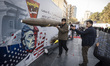 An unidentified man carries a scale model of an Iran-made ballistic missile in front of an...