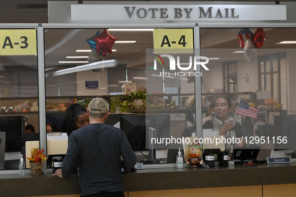 An election worker waves a US flag to assist ongoing mail-in voters during California's special election on Proposition 50, a measure that t... by Carlos Moreno/NurPhoto